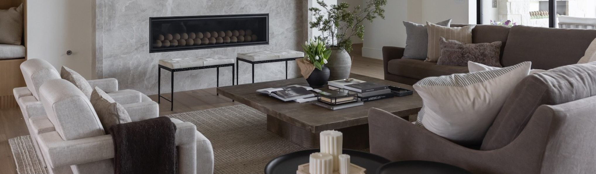 living room with a stone fireplace and neutral colored sofas and pillows