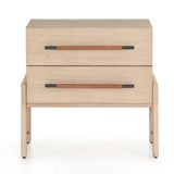 A light-finished oak nightstand with dual drawers featuring iron hardware wrapped in tan top-grain leather, with a clean silhouette and solid oak construction.