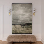An oversized wall art depicting a horse, framed in black, mounted above a bench on a wall with two sconces.