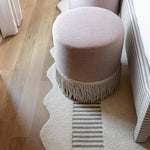 Pink stools with fringe on a light wooden floor and rug