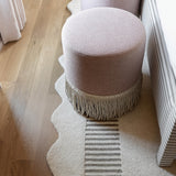 Pink stools with fringe on a light wooden floor and rug