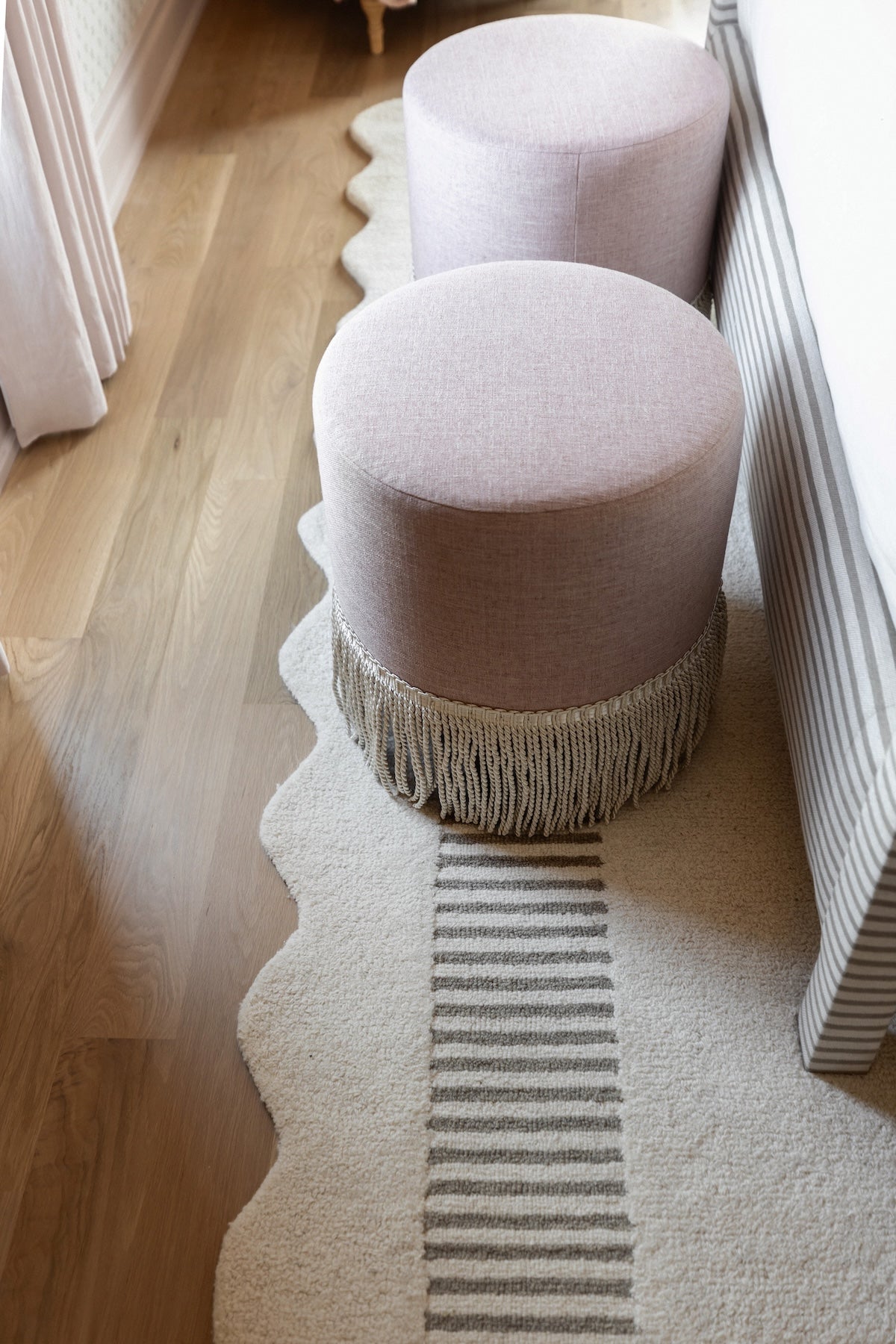 Pink stools with fringe on a light wooden floor and rug