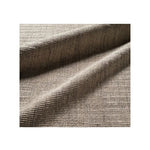 A close-up of textured woven area rug in a warm taupe-beige color, shown with soft folds and ribbed texture on a white background.