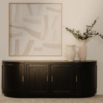 Nicola media tv cabinet against a wall with abstract art and a vase with greenery.