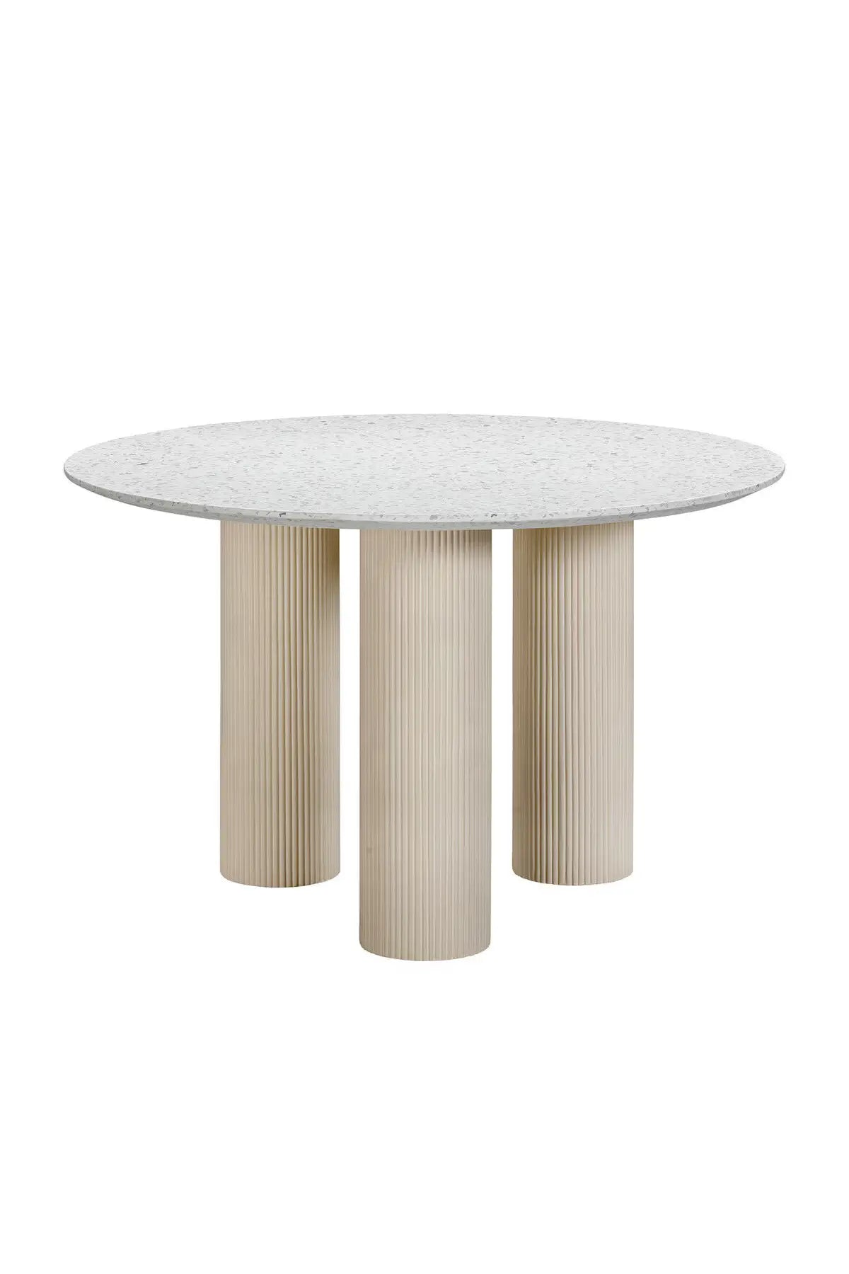 A round terrazzo concrete dining table with a pebble-polished top and fluted legs in a neutral color palette.