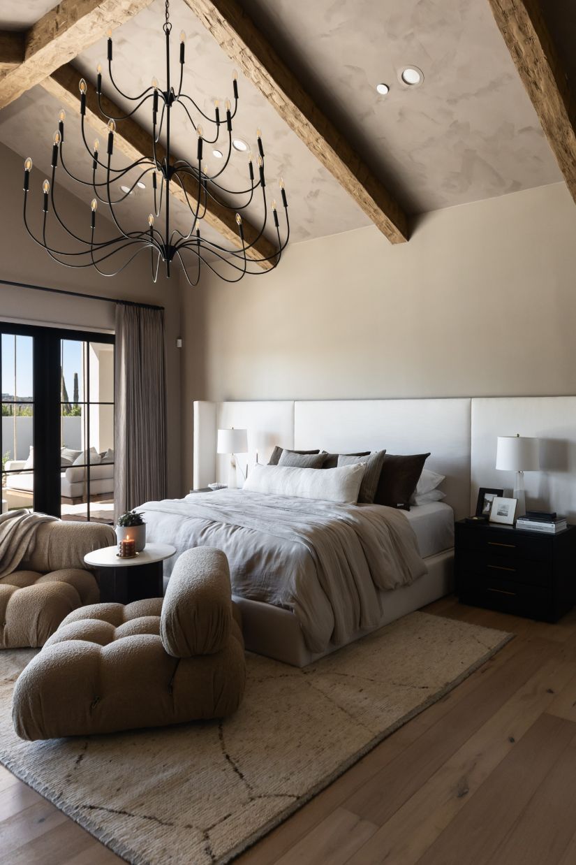 Modern bedroom with a Tirrell Large Black candle-style chandelier, bed, and sitting area.