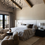 Modern bedroom with a Tirrell Large Black candle-style chandelier, bed, and sitting area.
