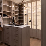 Modern walk-in closet with a Regina Andrew Talon modern chandelier shelves, drawers, and a central island.