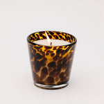 Scented candle in a tortoiseshell-patterned glass container on a white background